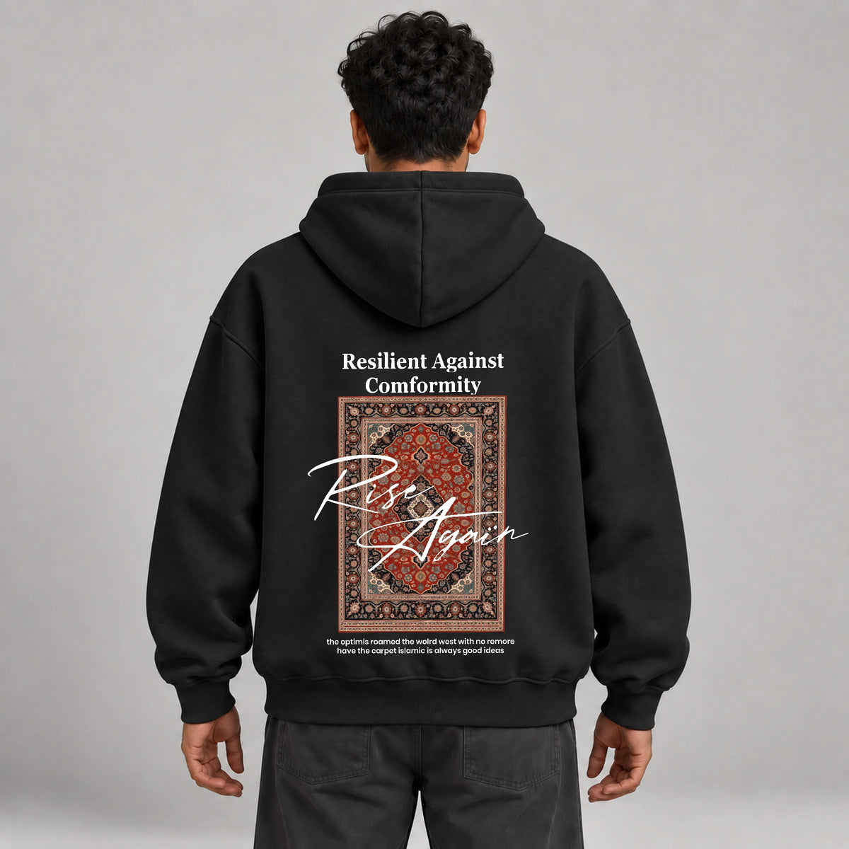 Model wearing KIFL Rise Again oversized hoodie in black – straight back view of carpet print