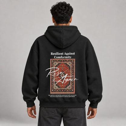 Model wearing KIFL Rise Again oversized hoodie in black – straight back view of carpet print